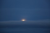 En altamar, la luna saliendo entre las nubes 